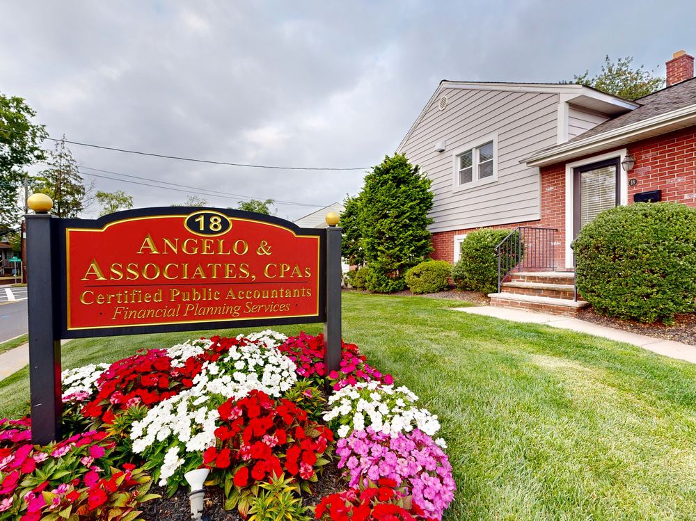 Angelo & Associates CPA office sign in front of their Clark, New Jersey building, surrounded by landscaped flower beds
