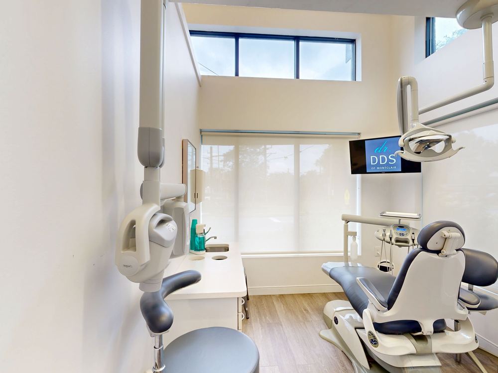 Modern dental treatment room at D'Amore Russo Dental Design Studio in Montclair, New Jersey, with dental chair, overhead lighting, and large windows
